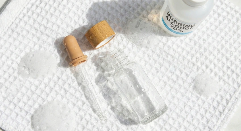 Flat lay of disassembled glass dropper bottle parts drying on a towel, illustrating the cleaning and sterilization process for reuse.
