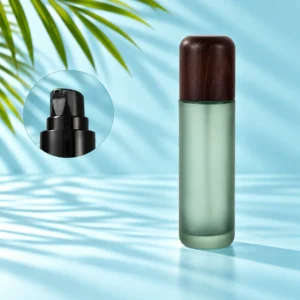 Frosted green glass lotion bottle with rounded dark wood cap and black pump detail inset on a light cyan scene with visible palm leaves