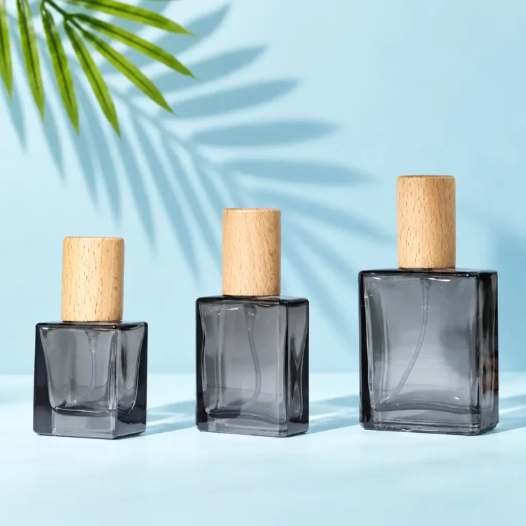 Smoke-gray square glass perfume bottles in three sizes with light wood caps