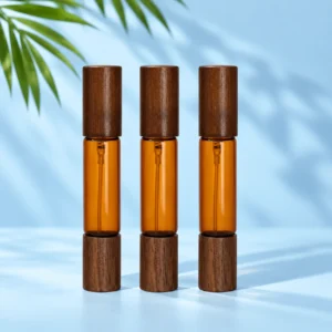 Three amber double ended glass perfume bottles with dark wood caps on both ends on a pale blue cyan tabletop