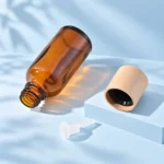 Amber glass bottle, natural wood cap and inner dispensing insert shown separately