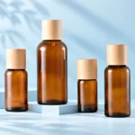 Four amber glass essential oil bottles with natural wood caps in varied sizes
