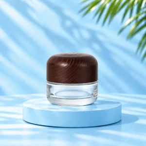 Clear glass cream jar with rounded dark wood lid on a cyan platform, nominal 50g version.