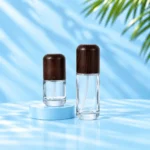 Two clear glass lotion bottles of different heights with rounded dark wood caps on cyan platforms.