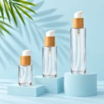 Clear glass lotion pump bottles with bamboo collars on a unified pale blue display