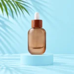 Frosted brown glass dropper bottle with reddish sapele wood collar and white bulb on a pale blue platform.