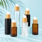 Glass lotion pump bottles in black, amber, clear and frosted finishes with bamboo collars