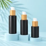 Matte black glass lotion pump bottles with bamboo collars on pale blue display blocks