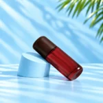 Red glass lotion bottle with a rounded dark wood cap displayed at an angle on a cyan cylinder.