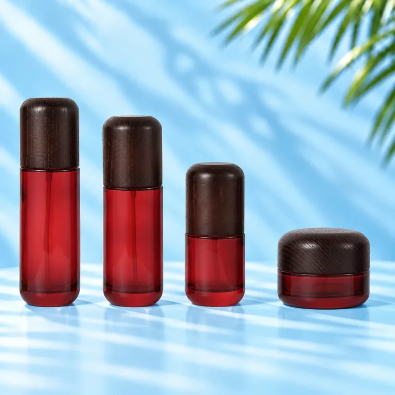 Three red glass lotion bottles and one matching red glass cream jar with rounded dark wood closures on a cyan tabletop.