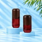 Two compact red glass lotion bottles with rounded dark wood caps displayed on cyan platforms.