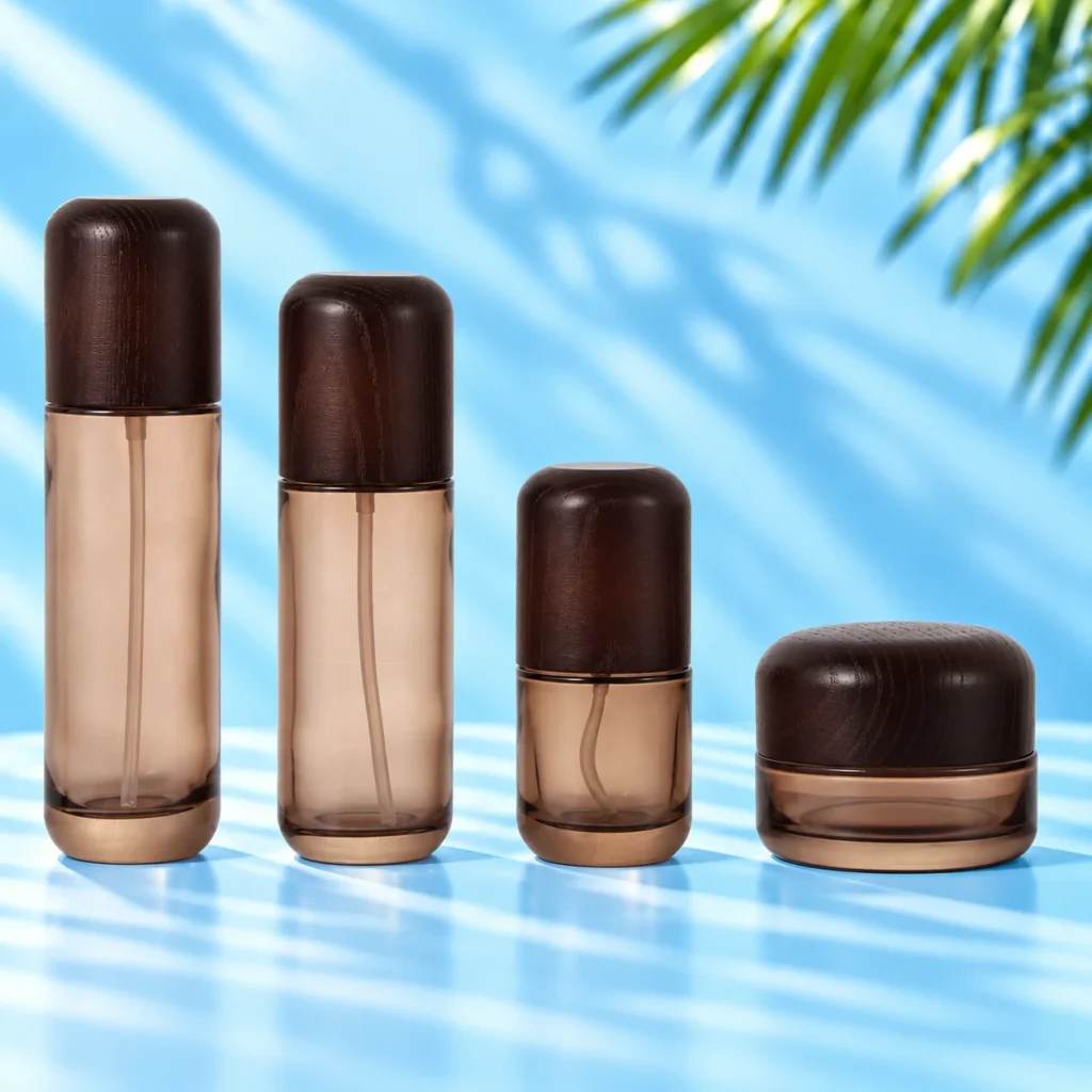 Three smoke gray glass lotion bottles and a matching cream jar with rounded wood closures on a cyan tabletop.