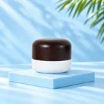 Compact opaque white cream jar with rounded dark solid wood lid on a pale blue cyan platform. Nominal 30g version.