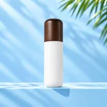 Single opaque white lotion bottle with rounded dark wood cap on a cyan tabletop beneath palm foliage.