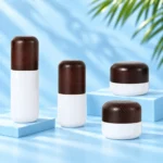 Two opaque white lotion bottles and two white cream jars with matching rounded dark solid wood closures on cyan platforms.